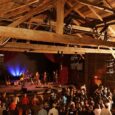 Grange en bois transformée en salle de concert, avec public et scène