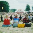 Public assis dans l’herbe devant une scène lors d’un festival