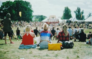 Public assis dans l’herbe devant une scène lors d’un festival